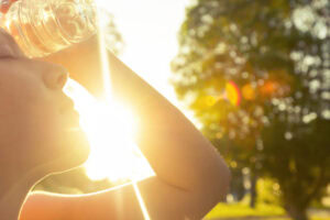 Woman outside in the heat, using water bottle to cool down.