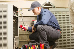 HVAC repairman works on a home's air conditioner unit outdoors.